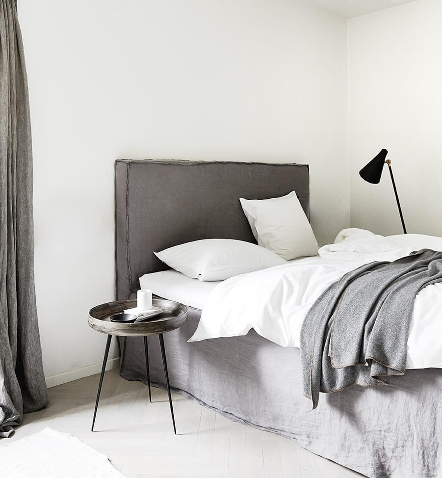 Schlafzimmer skandinavisch einrichten: Leinenbettwäsche, eine Designerleuchte, ein kleiner Seitentisch als Nachttisch