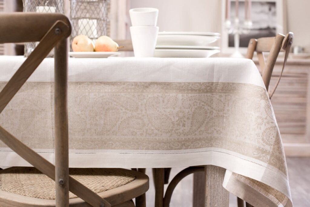 Leinentischwäsche ist haltbar und sieht natürlich aus. Hier eine Tischdecke mit edlem Ajoursaum und sandfarbenem Paisley-Mäander