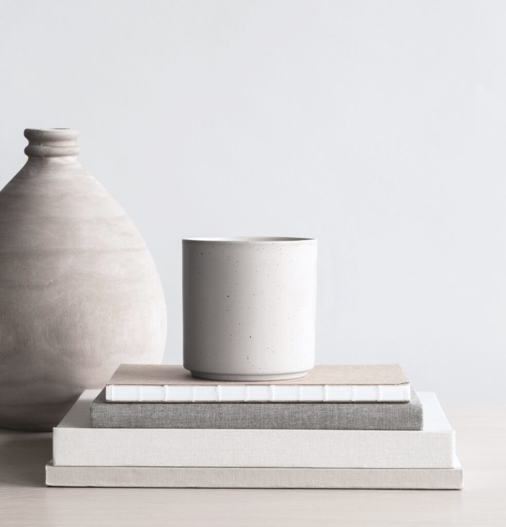 Wohntrend: weniger haben. Minimalistische Deko gelingt mit Alltagsgegenständen, die du in Gruppen zusammenfügst - hier sind es Bücher mit Leineneinband und dazu passende Gefäße aus Ton