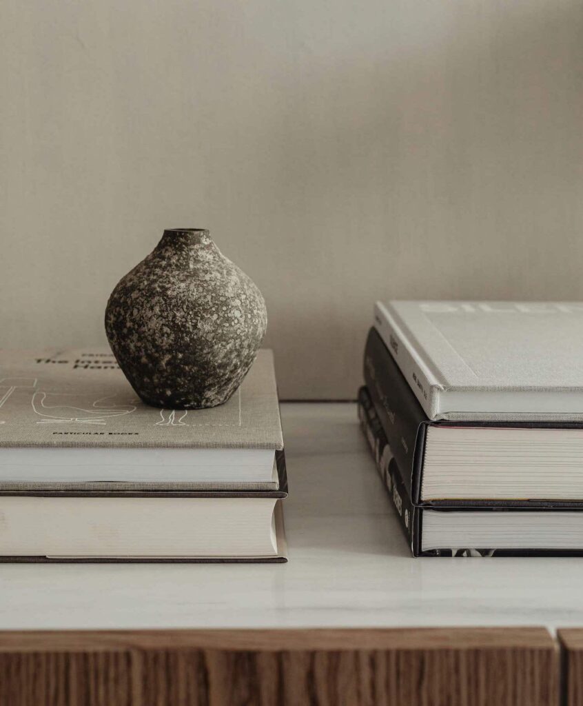 Eine kleine Sammlung an persönlichen Dingen und Lieblingsbüchern auf einem Sideboard. So geht zuhause Wohlfühlen - auch in einem minimalistischen Schlafzimmer