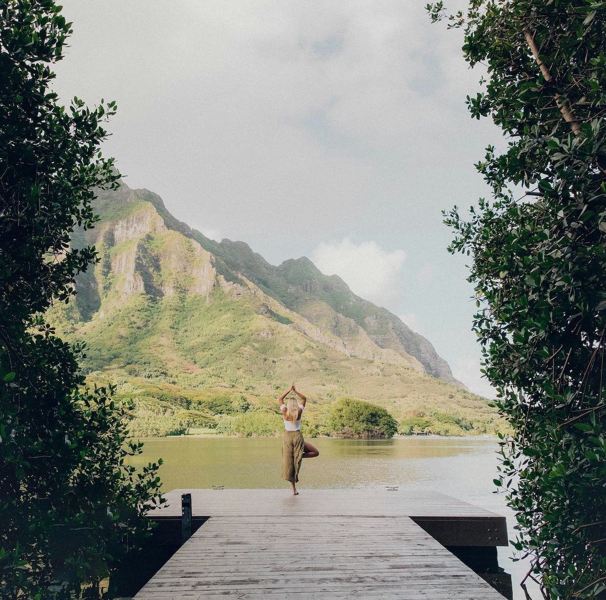 Wege aus der Reizüberflutung - Ein Tag am See. Den Tag am Wasser begrüßen, so wie diese Frau, die gerade Yoga auf einem Steg macht