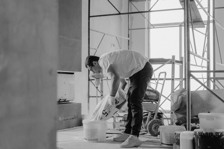 Ein Arbeiter auf einer Baustelle. Zu sehen sind Baugerüste, Baueimer und Baumaterial